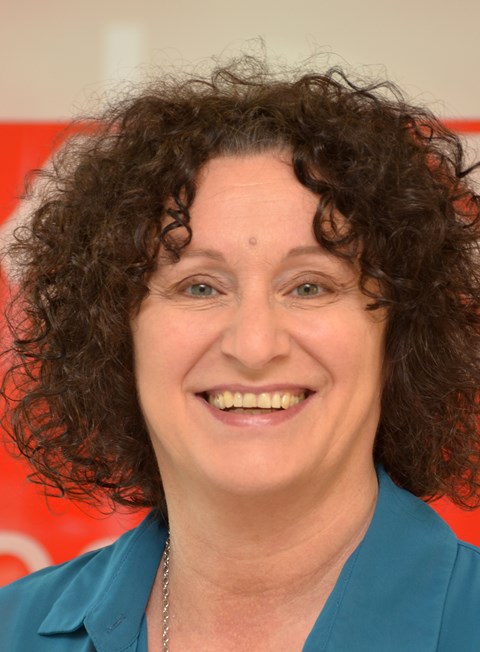 Eine Person mit lockigem Haar und einem blauen Oberteil. 